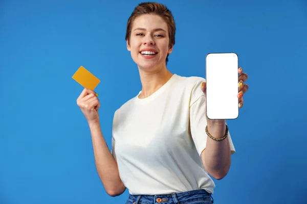 Happy nő mutatja üres okostelefon képernyő kék háttér — Stock Fotó