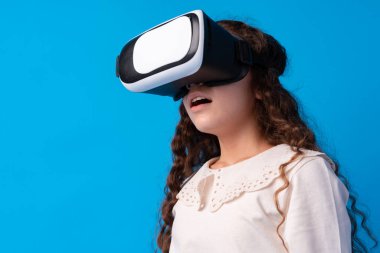 Mavi arka planda sanal gerçeklik gözlüklü kız.