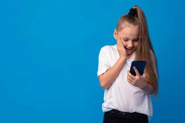 Menina usando telefone móvel.Contra fundo azul — Fotografia de Stock