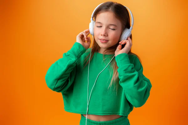Retrato de chica adolescente feliz moderna con auriculares sobre fondo naranja —  Fotos de Stock
