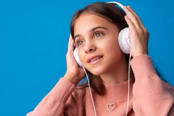 Uczennica ze słuchawkami słuchająca muzyki na niebieskim tle — Zdjęcie stockowe