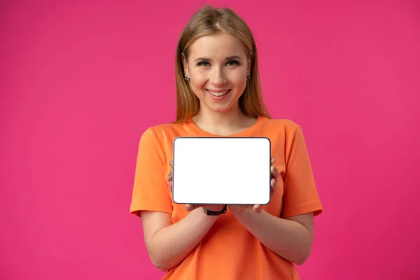 Mujer caucásica joven señalando su tableta digital con pantalla en blanco para su diseño en el fondo de color — Foto de Stock