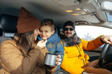 Anne, baba ve çocuk kışın dağlara tatile gitmek için arabayla seyahat ediyorlar.