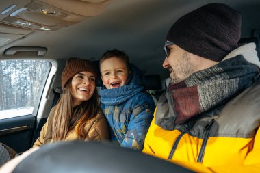 Anne, baba ve çocuk kışın dağlara tatile gitmek için arabayla seyahat ediyorlar.