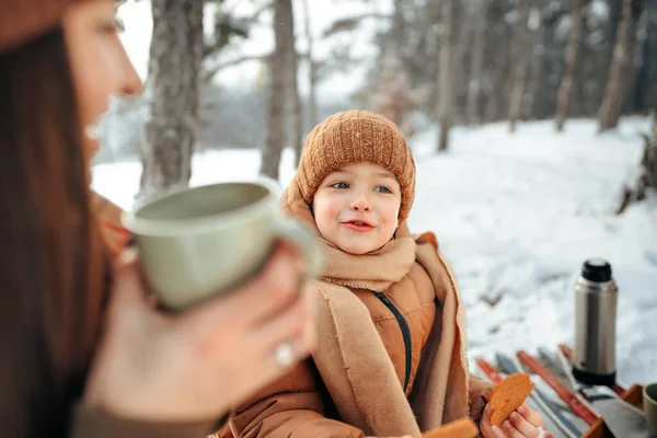 Young woman with a son in winter forest on a picnic drink hot tea — Stock Photo, Image
