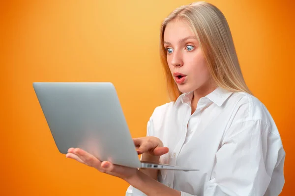 Retrato de uma menina adolescente alegre segurando computador portátil contra fundo laranja — Fotografia de Stock