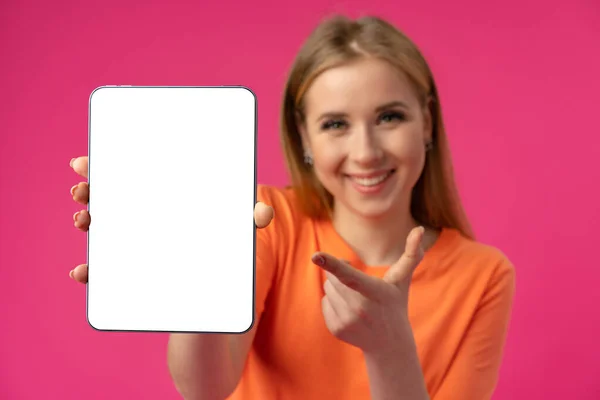 Mujer caucásica joven señalando su tableta digital con pantalla en blanco para su diseño en el fondo de color — Foto de Stock