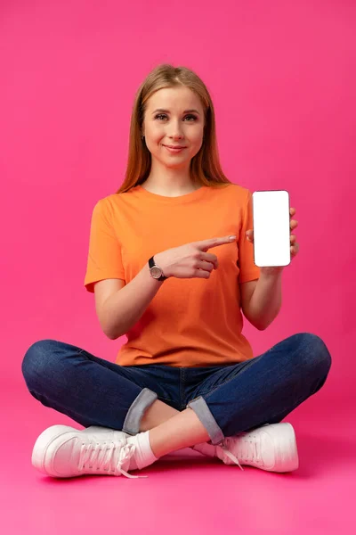 若いです女性は、色の背景に隔離された白い画面でスマートフォンを示す — ストック写真