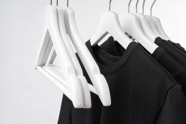 Black T-shirt on hangers on metal rack isolated on white background — Stock Photo, Image