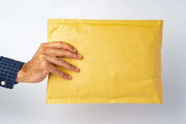 Männliche Hand hält Paketpost vor weißem Hintergrund — Stockfoto