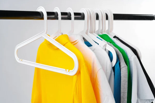 Kleding hangen op kledingrek over witte achtergrond. — Stockfoto