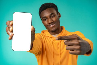 Stüdyodaki boş beyaz cep telefonu ekranına gülümseyen sıradan bir zenci.