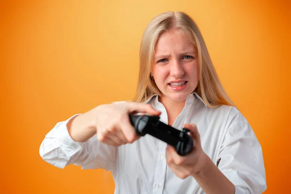 Jovem menina bonita adolescente jogando com console joystick sobre fundo laranja — Fotografia de Stock