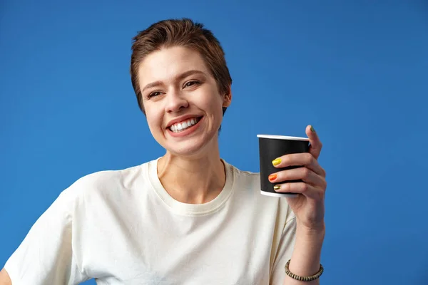 Gyönyörű mosolygós nő iszik kávét a kék háttér — Stock Fotó
