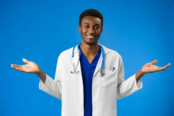Afroamerikanischer Arzt mit Stethoskop vor blauem Hintergrund, ahnungslos mit erhobenen Armen — Stockfoto