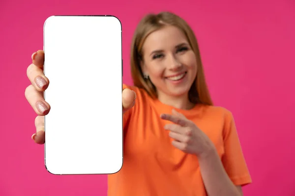 Mladá žena ukazuje smartphone s izolovanou bílou obrazovkou na barevném pozadí — Stock fotografie