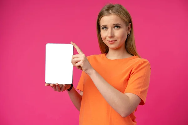 Mujer caucásica joven señalando su tableta digital con pantalla en blanco para su diseño en el fondo de color — Foto de Stock