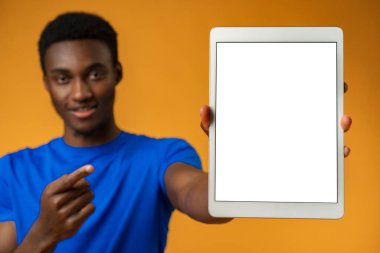 Afrikalı Amerikalı adam sarı stüdyoda boş dijital tablet ekranı gösteriyor..