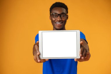 Afrikalı Amerikalı adam sarı stüdyoda boş dijital tablet ekranı gösteriyor..