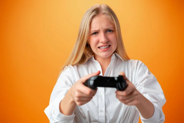 Jovem menina bonita adolescente jogando com console joystick sobre fundo laranja — Fotografia de Stock