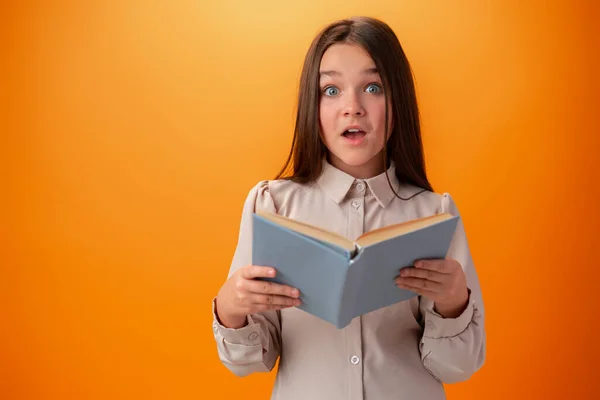 Turuncu arka planda kitapları olan zeki bir genç kızın portresi. — Stok fotoğraf