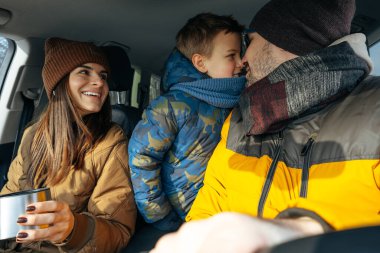 Anne, baba ve çocuk kışın dağlara tatile gitmek için arabayla seyahat ediyorlar.