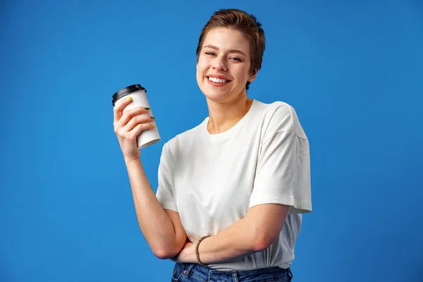 Gyönyörű mosolygós nő iszik kávét a kék háttér — Stock Fotó