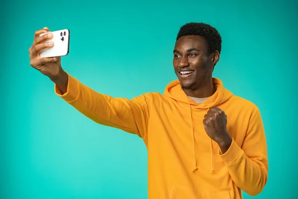 Excited black man reading good news on cellphone in studio