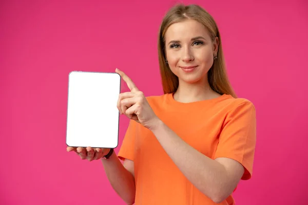 Young caucasian woman pointing her digital tablet with blank screen for your design on color background — Stock Photo, Image