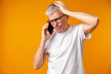 Endişeli ve şaşkın kıdemli adam akıllı telefon kullanıyor.