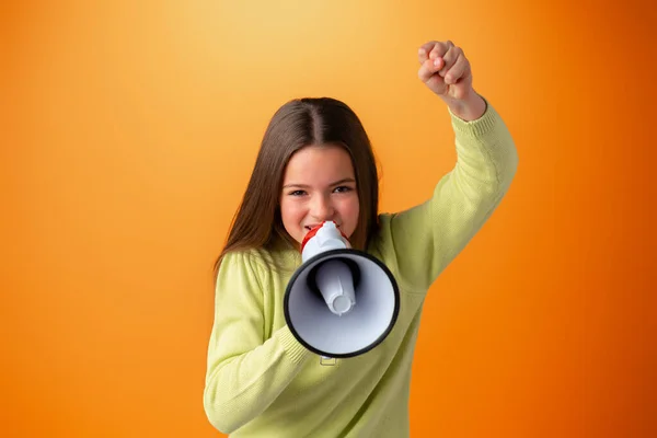 Teenager-Mädchen macht Ansage mit Megafon vor orangefarbenem Hintergrund — Stockfoto