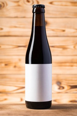 Ahşap arka plandaki bira şişesinde boş etiket var..