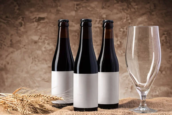 Botella de cerveza y vaso de cerveza contra fondo gris — Foto de Stock