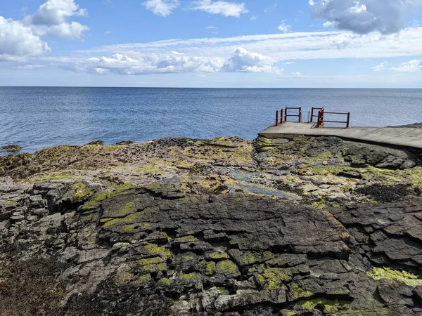 Deniz ve gökyüzü ile kayalık sahil manzarası