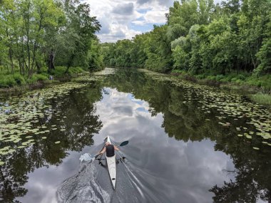 rear view of man is floating on a canoe along the river