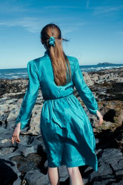beautiful young woman posing on a rock near the sea.