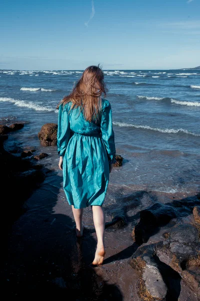 Kumsalda mavi elbiseli genç bir kadın.