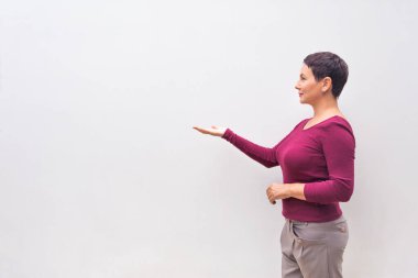 Kadın telif alanıyla sağ tarafı işaret ediyor, beyaz bir duvara karşı.