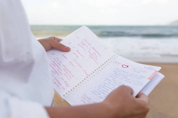 Caderno, mulher ler suas notas perto do mar — Fotografia de Stock