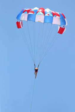 Bir kadın bulutlu mavi gökyüzünün arka planında paraşütle süzülüyor..