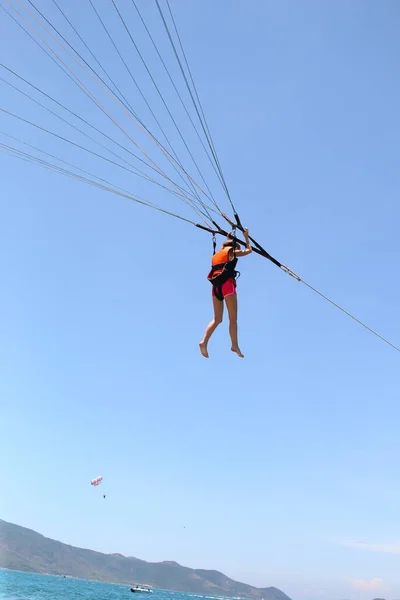 Жінка ковзає, використовуючи парашут на тлі хмарного блакитного неба . — стокове фото