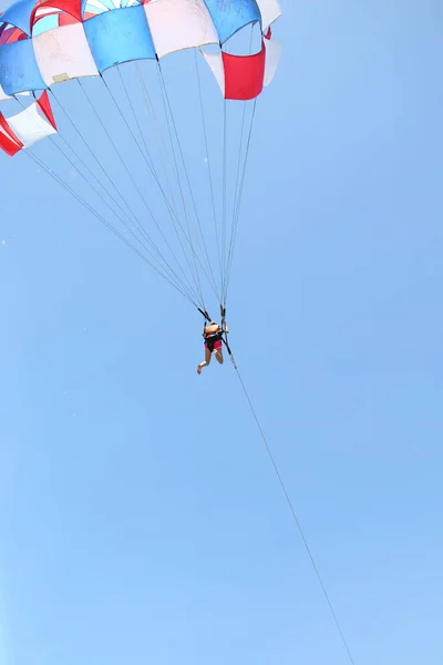 구름낀 푸른 하늘 배경에 낙하산을 사용하여 활공하고 있는 여자. — 스톡 사진