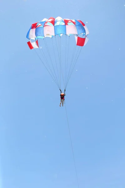 Een vrouw glijdt met een parachute op de achtergrond van de bewolkte blauwe lucht. — Stockfoto