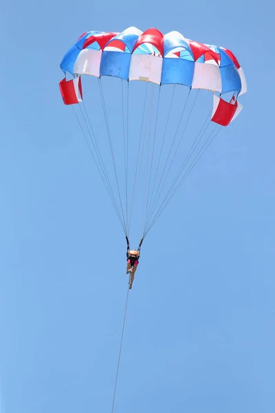 En kvinna glider med hjälp av en fallskärm på bakgrunden av molnigt blå himmel. — Stockfoto
