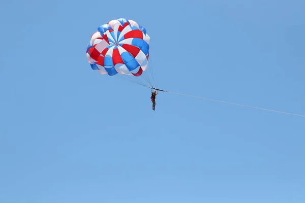 Жінка ковзає, використовуючи парашут на тлі хмарного блакитного неба . — стокове фото