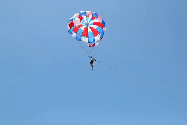 Bir kadın bulutlu mavi gökyüzünün arka planında paraşütle süzülüyor.. — Stok fotoğraf