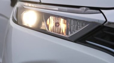 Beyaz bir arabanın farları açılıp kapanıyor.