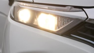 Beyaz bir arabanın farları açılıp kapanıyor.