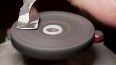 Küçük bir elektrikli çarkın metal parçasını bilemek.