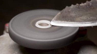 Küçük elektrikli bir tekerlekte eski metal bir bıçağı bilemek.